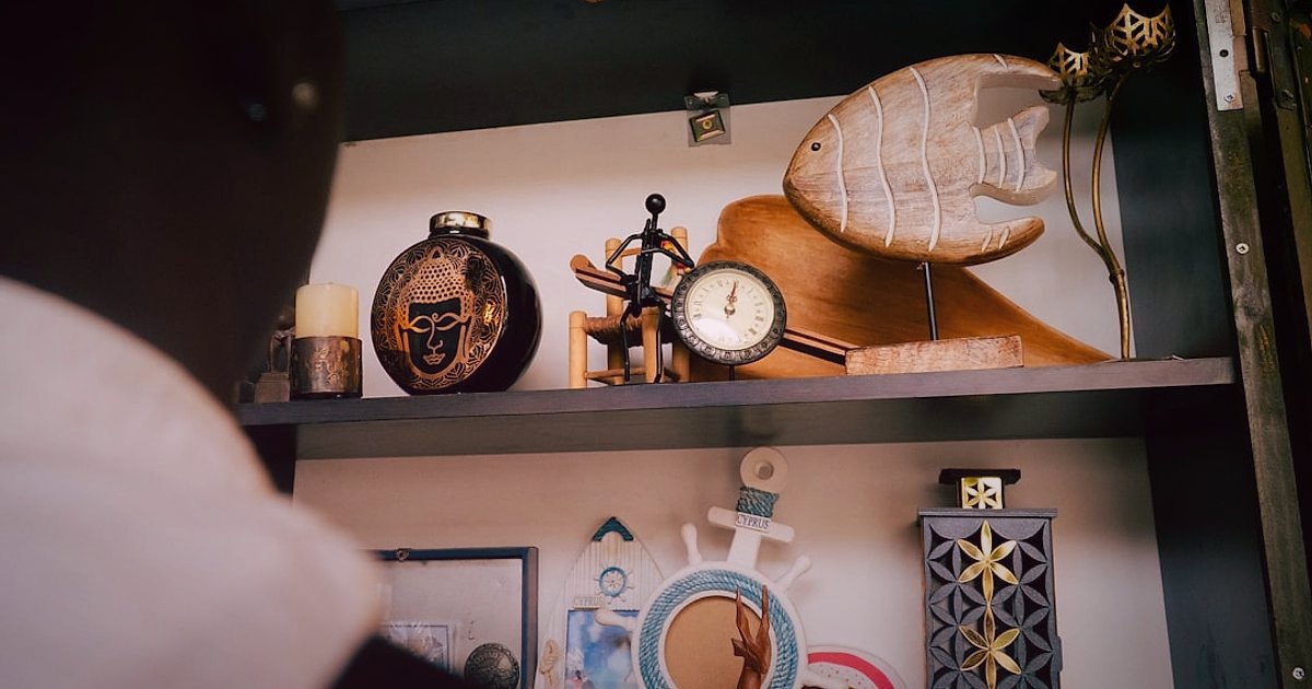 2026 Mobilya & Dekorasyon: Kâr Marjı ve Fiyatlandırma Stratejileri - man meticulously arranging small decorative items on a shelf
