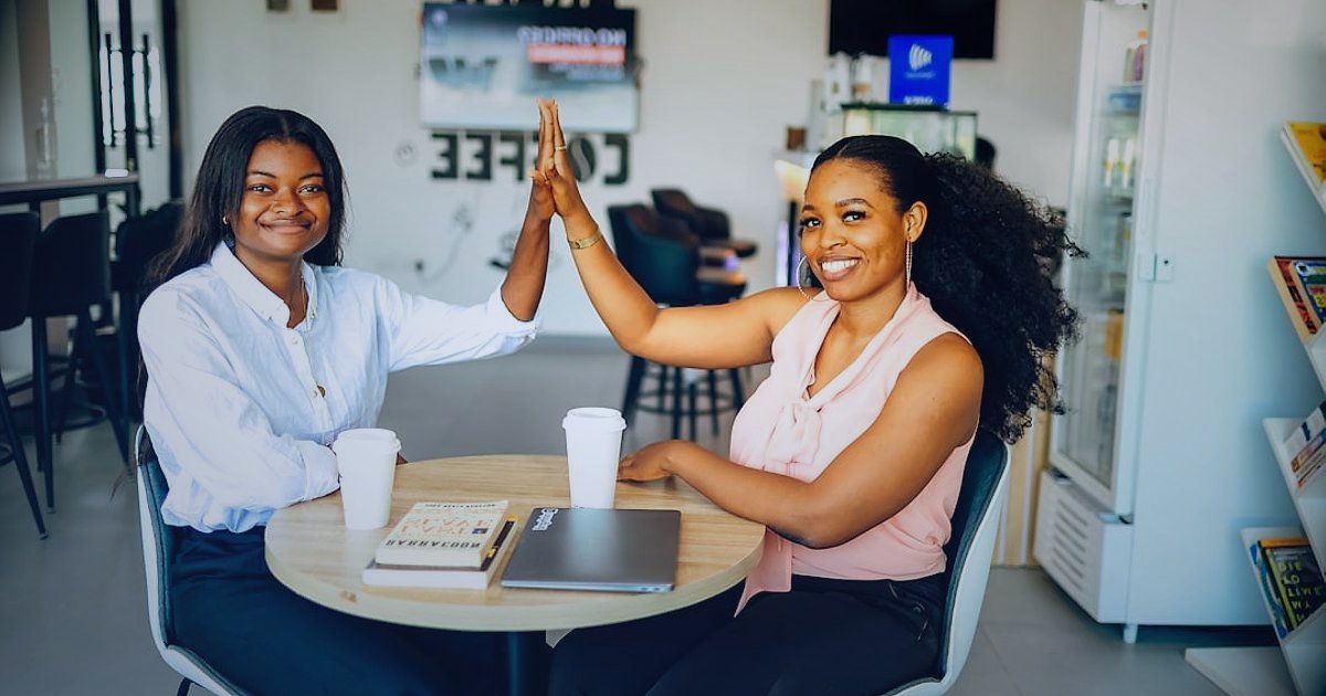 2026'da Zirveye Çıkın: Dropshipping Tedarikçi Firmaları Rehberi - two business owners smiling, shaking hands over a cafe table, laptop and coffee present, signifying a successful partnership