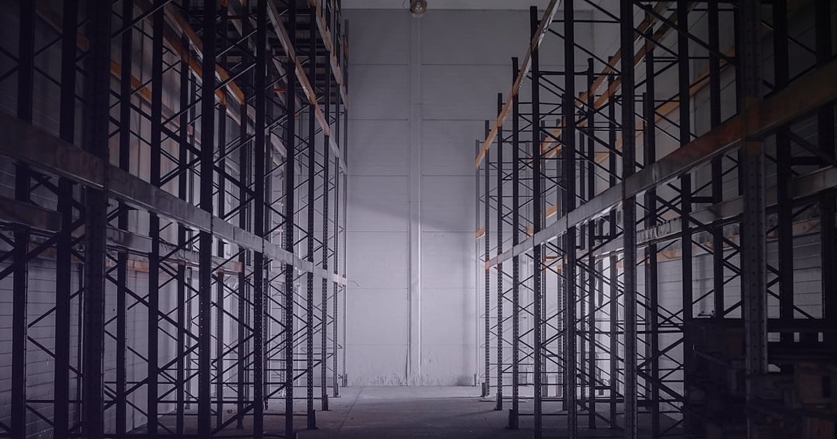 Dropshipping Avantajları & Dezavantajları 2026: Karlı Bir Başlangıç Rehberi - empty warehouse shelves with single box dramatically lit