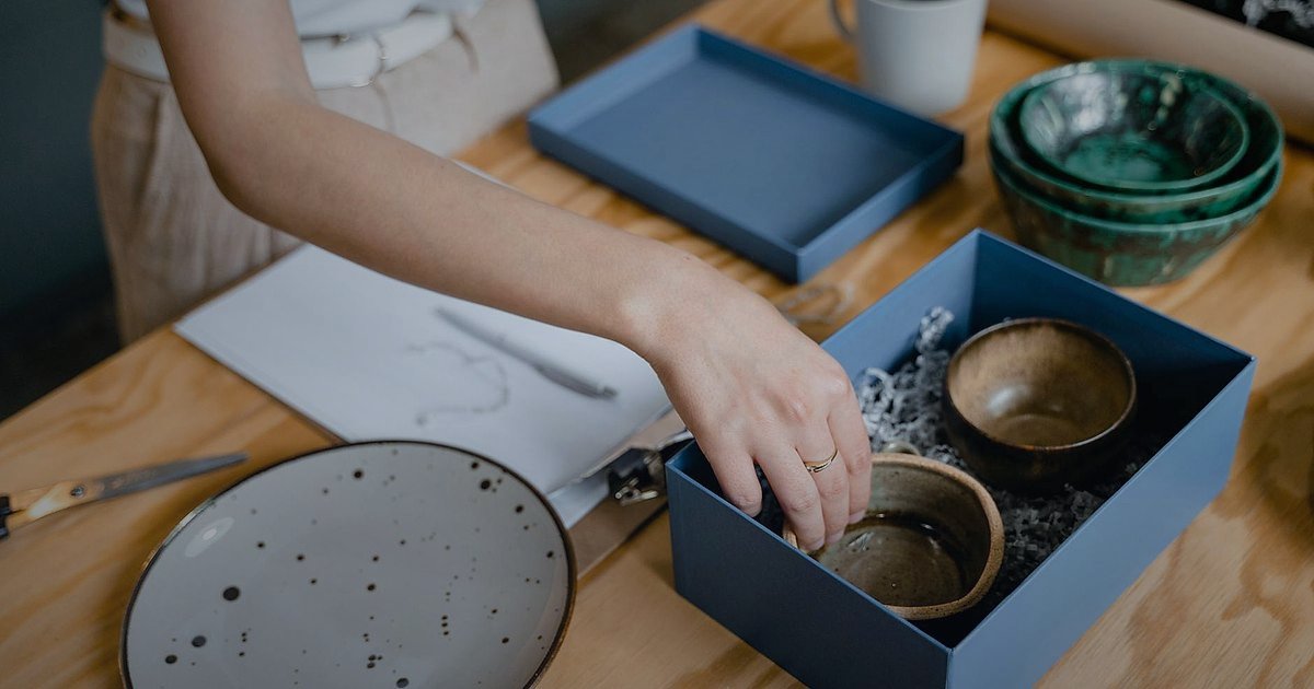 Dropshipping Nedir 2026? Stoksuz Satışla Kârlı E-Ticaretin Sırları - person carefully arranging multiple small product boxes on a white surface