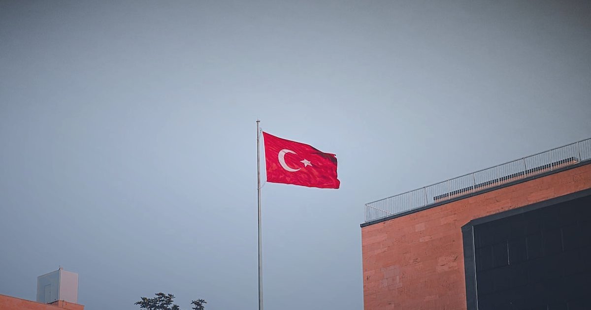 Dropshipping Tedarikçileri 2026: Güvenilir Partnerlerle Karlı Başlangıç Rehberi - Turkish flag waving next to a modern warehouse exterior