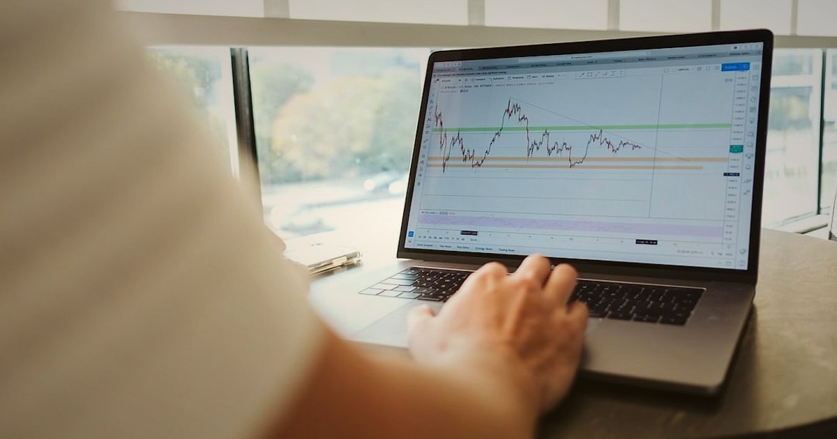 Dropshipping'e 2026'da Başlangıç: Karlı Bir E-Ticaret İmparatorluğu Kurun - Close-up of a person's hands typing on a laptop keyboard with financial graphs on the screen