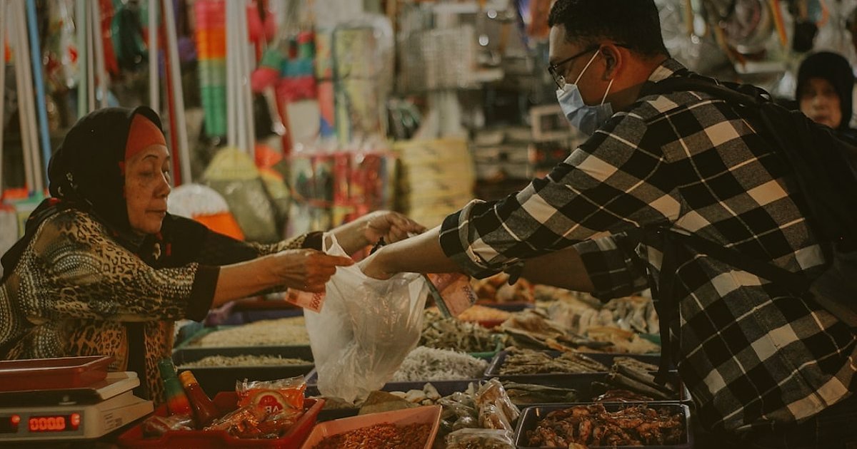 Dropshipping.gen.tr Avantajları 2026: Neden E-Ticarette Lideriz? - busy marketplace stall with various products and a vendor interacting with a customer