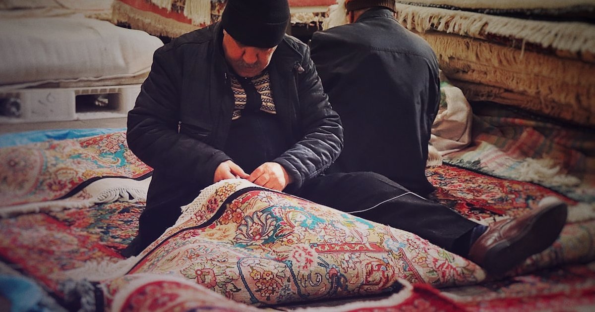Halı Satışında Kâr Marjı ve Fiyat Belirleme: 2026 Rehberi ile Maksimum Kazanç - warehouse worker carefully inspecting rolled traditional Turkish carpets