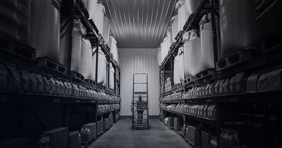 Kadın Giyim Pazaryeri Seçimi 2026: Komisyonlar ve Başarı Rehberi - Person arranging small boxes on a shelf in a clean, organized warehouse