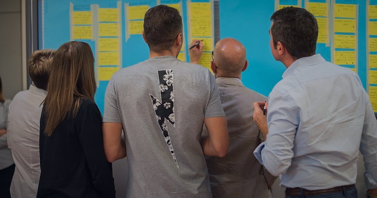Mobilya Dropshipping Stok Yönetimi 2026: Tedarik Zinciri Sırları - team members collaborating around a whiteboard with sticky notes